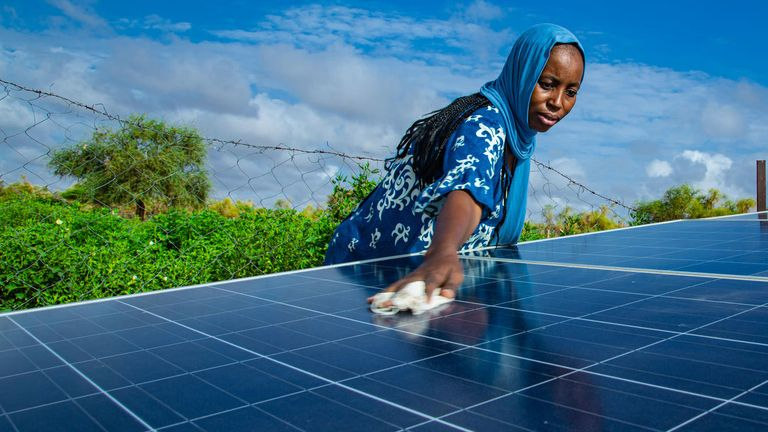 A woman cleans the solar panels in her neighborhood in Mauritania